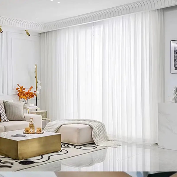 Cortina de tule voile instalada em uma sala de estar, trazendo sofisticação e leveza ao ambiente.