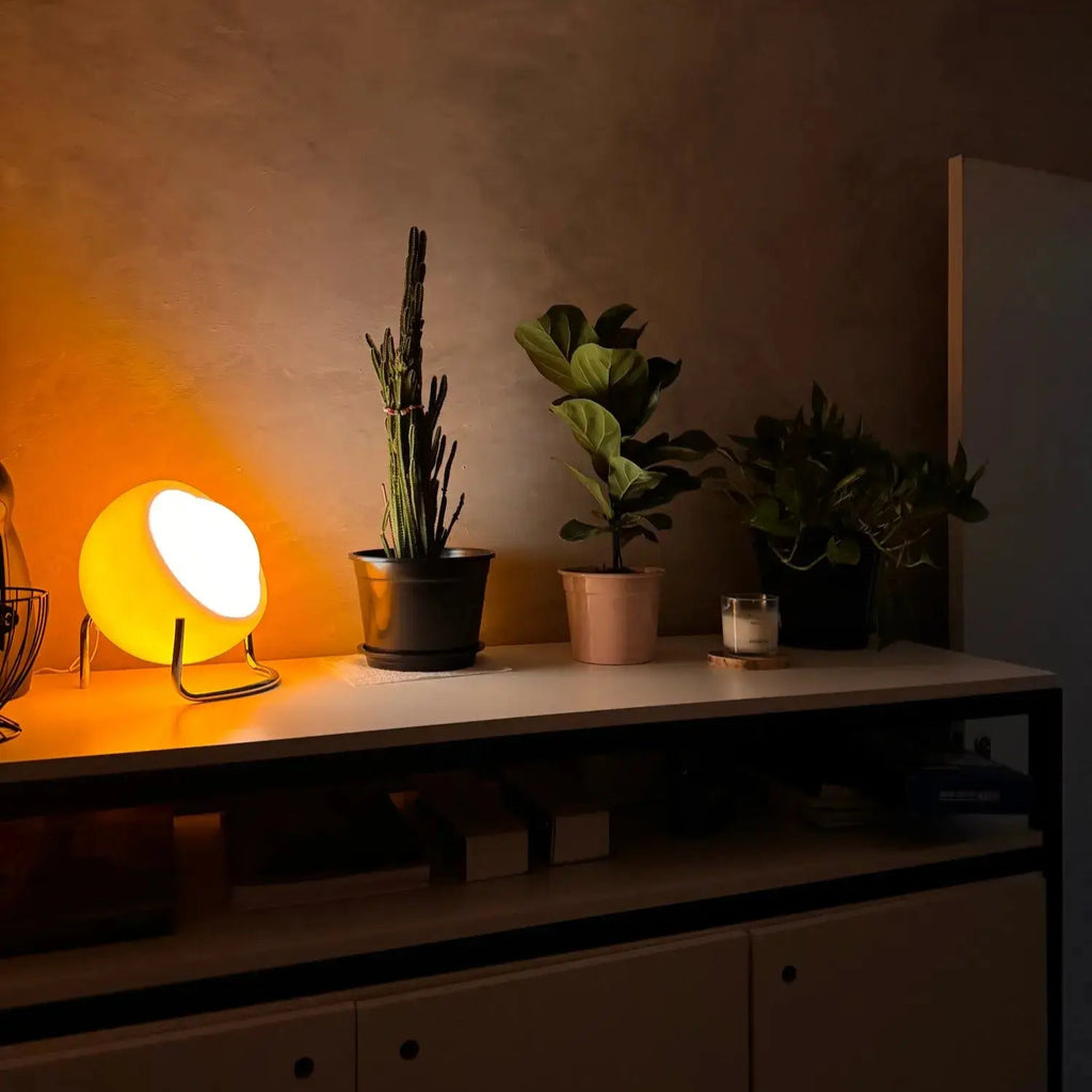 Luminária de Mesa Bauhaus Medieval LED exibida em ambiente interno, combinando o charme retro com a elegância nórdica. Seu abajur em vidro claro do leite e base texturizada em aço inoxidável proporcionam uma iluminação suave e sofisticada.