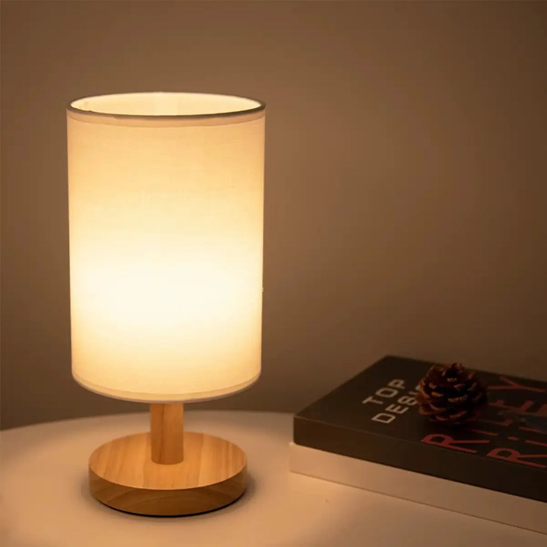 Detalhe do abajur de linho e da base de madeira maciça, demonstrando o acabamento sofisticado e minimalista da luminária.