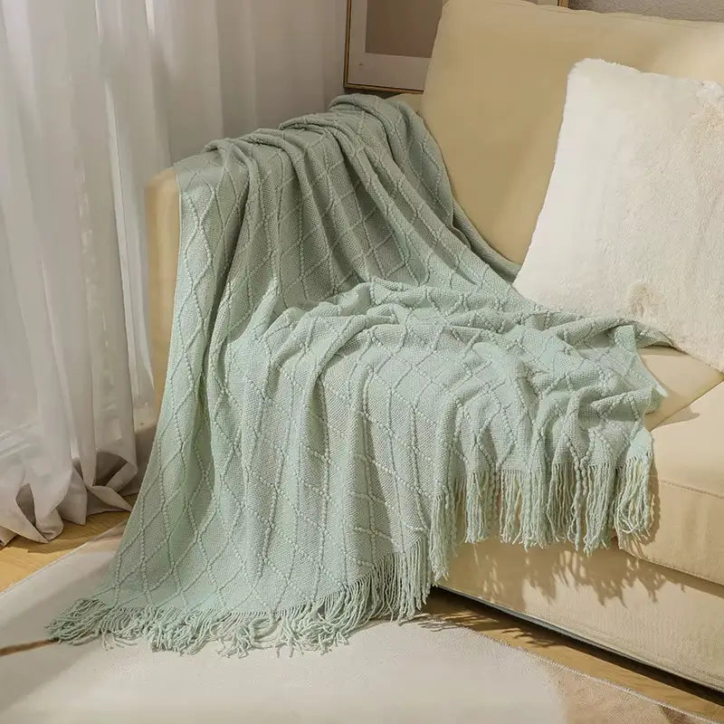 Manta de malha clássica com franjas, sinônimo de elegância e aconchego.