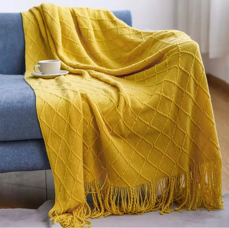 Manta de malha clássica com franjas, valorizando a sala de estar com elegância.